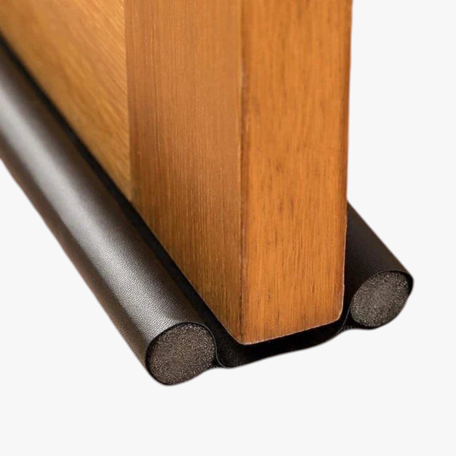 Roselva double-sided foam door bottom seal strip in black installed on a wooden door to block drafts and noise.